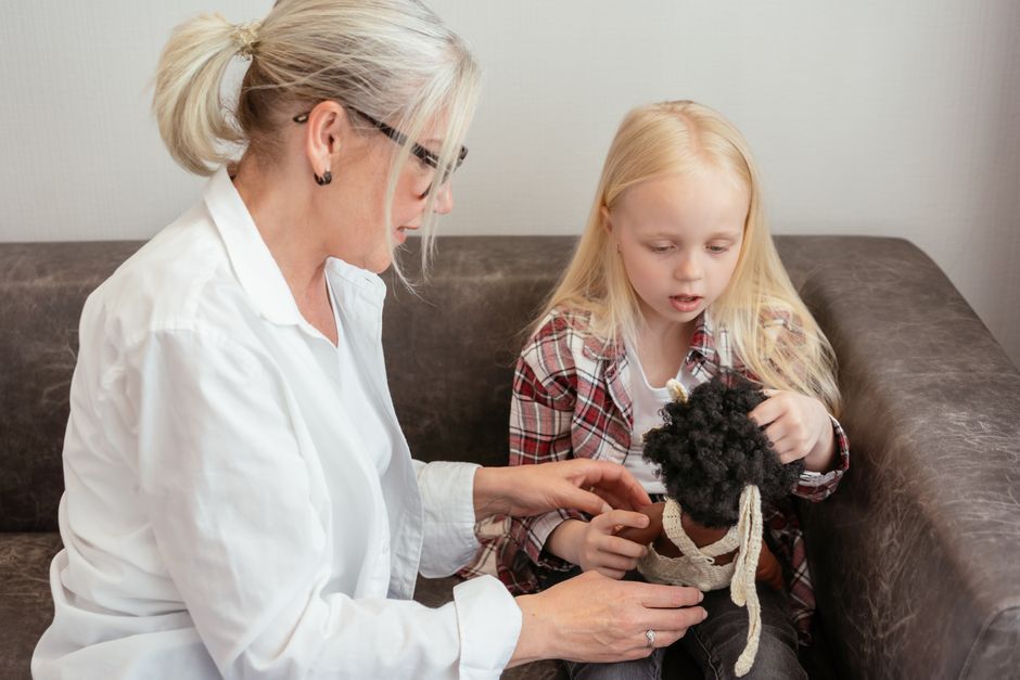An adult teaching a young child a new skill with toys at home