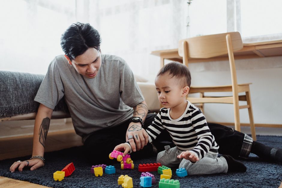 Parent and young child looking at each other and playing on the floor at home