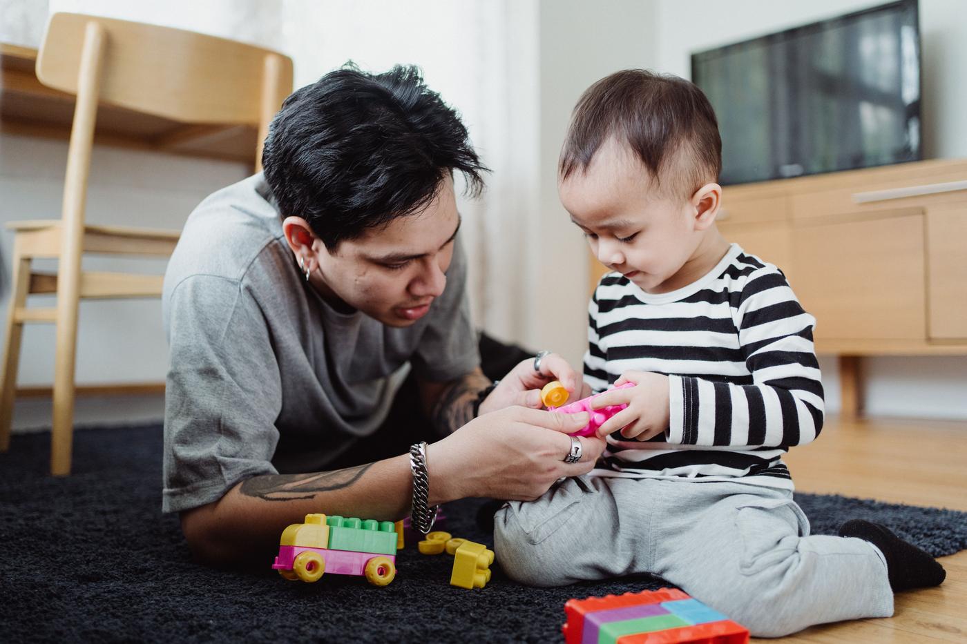 A loving father and his young son bonding while playing with toys on the floor