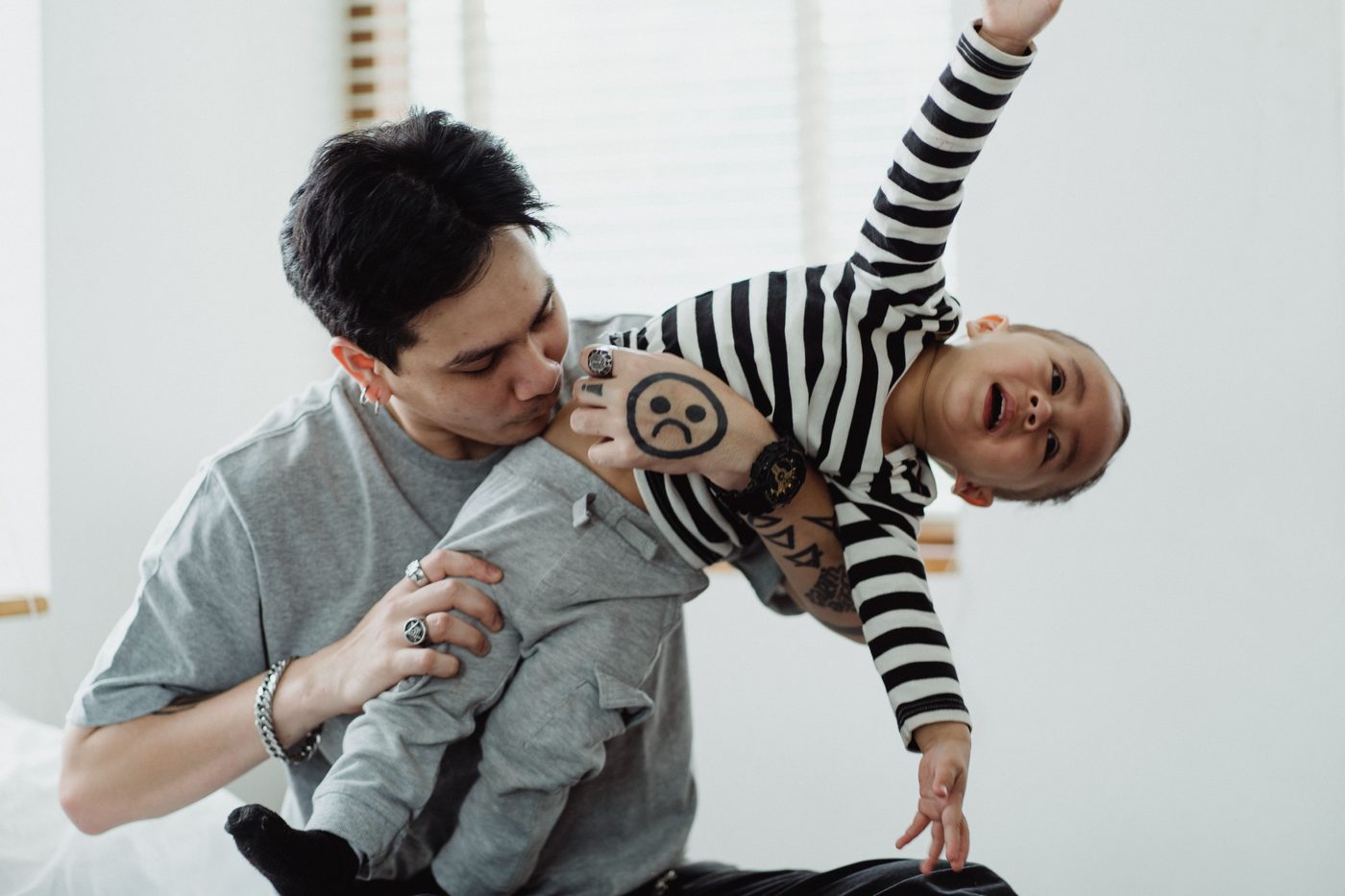 A father playfully holding his young son indoors