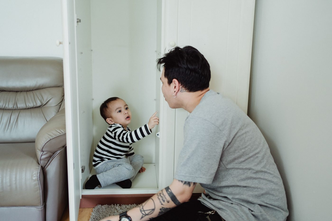 Father and baby bonding with playful moments indoors beside a comfortable couch