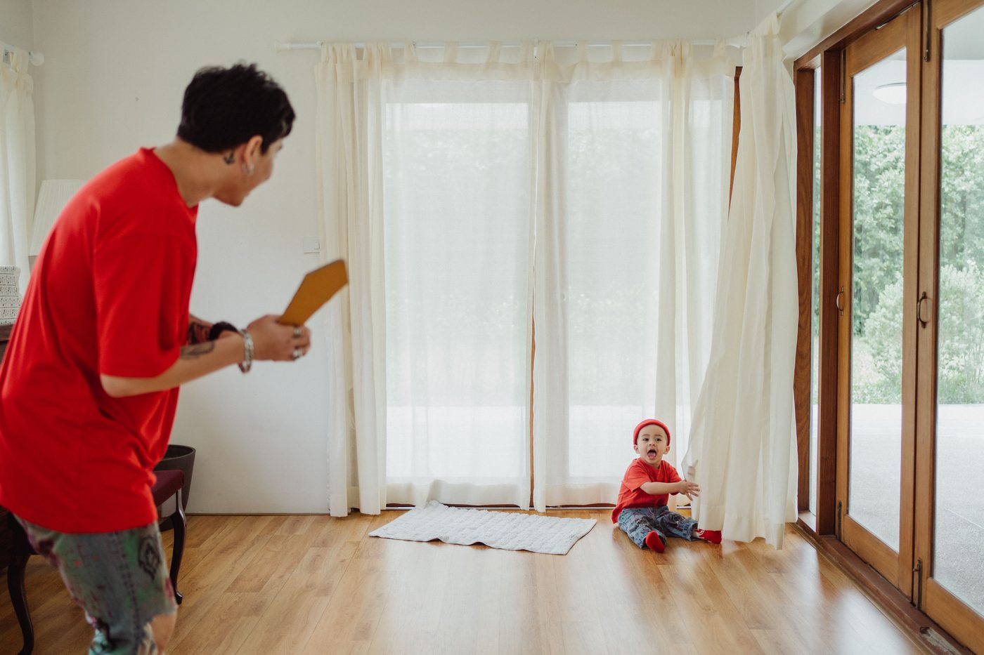 A joyful father and baby enjoying playtime indoors in matching red outfits
