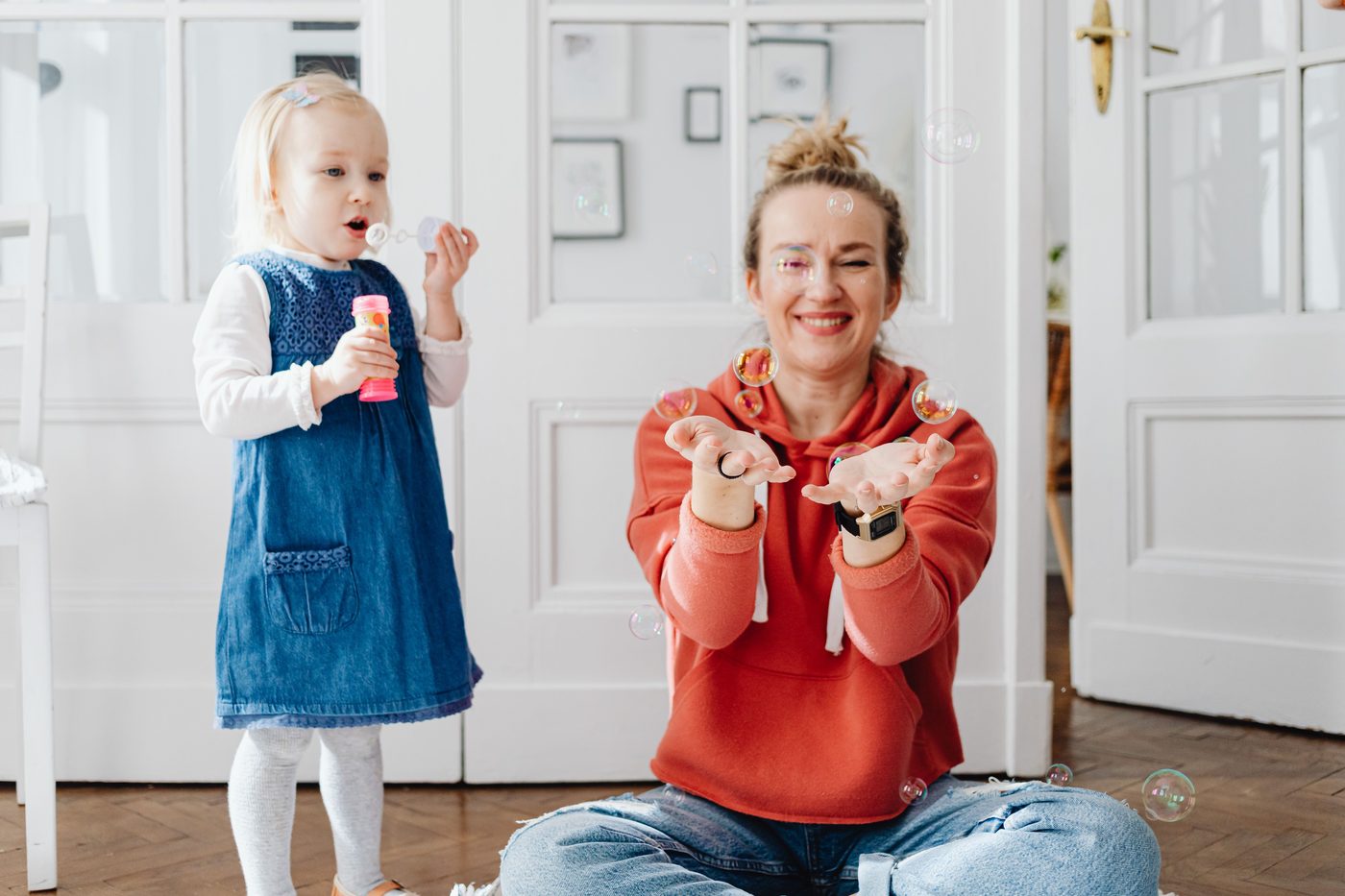 Smiling mother and child playing with bubbles indoors