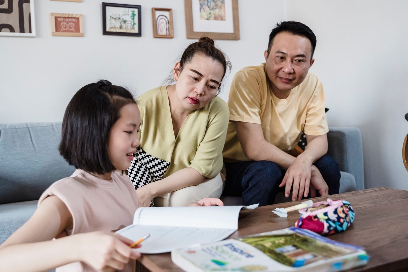 Parents assisting daughter with her homework in a cozy living room setting