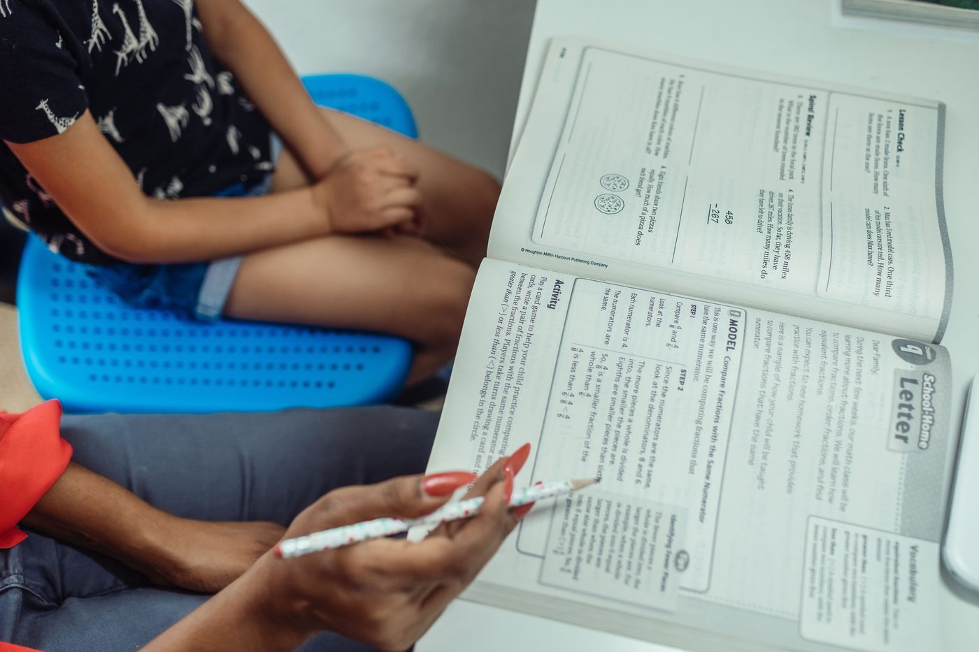 An educational scene with a teacher guiding a student through a textbook