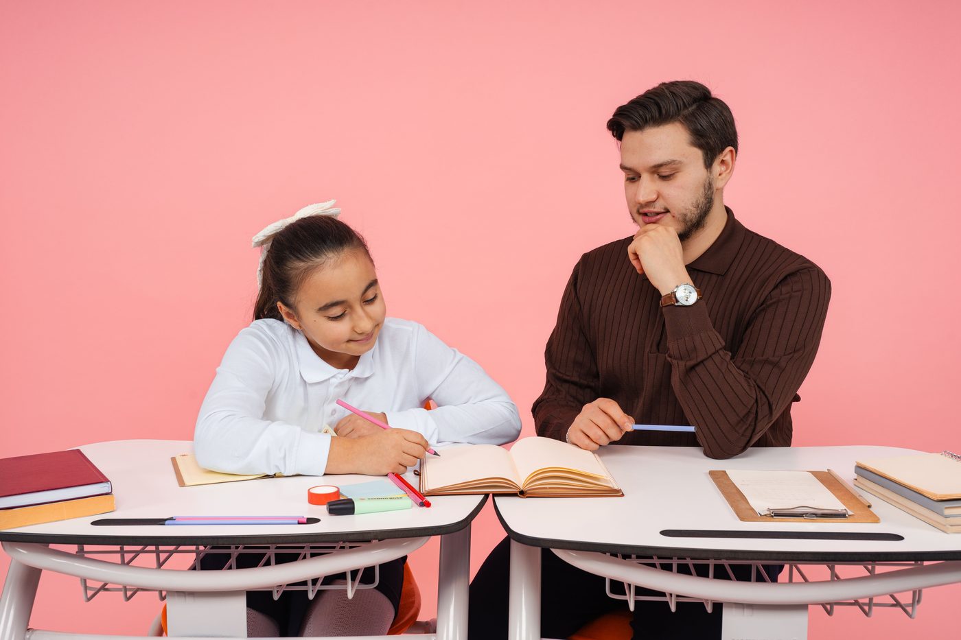 A teacher helps a student with schoolwork in an indoor learning environment