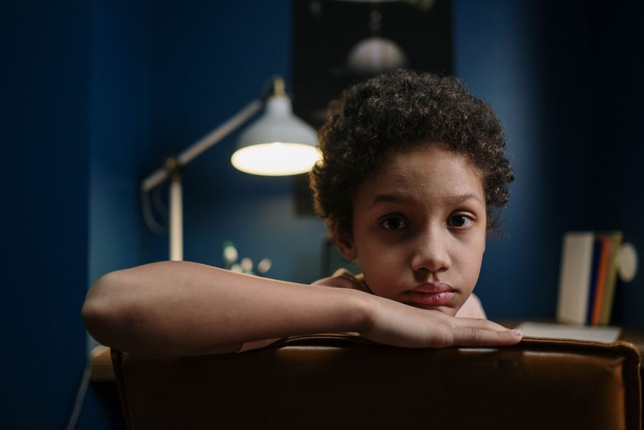 School-age child sitting quietly apart from a group of other children