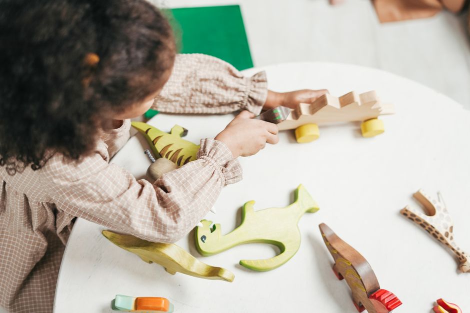 Toddler playing with toys on the floor while a parent watches closely