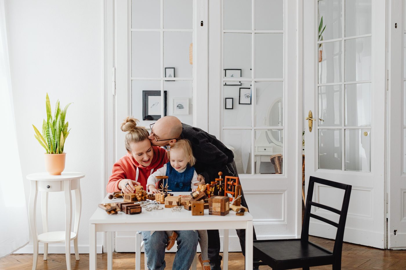 A loving family enjoying playtime with wooden toys in a cozy indoor setting