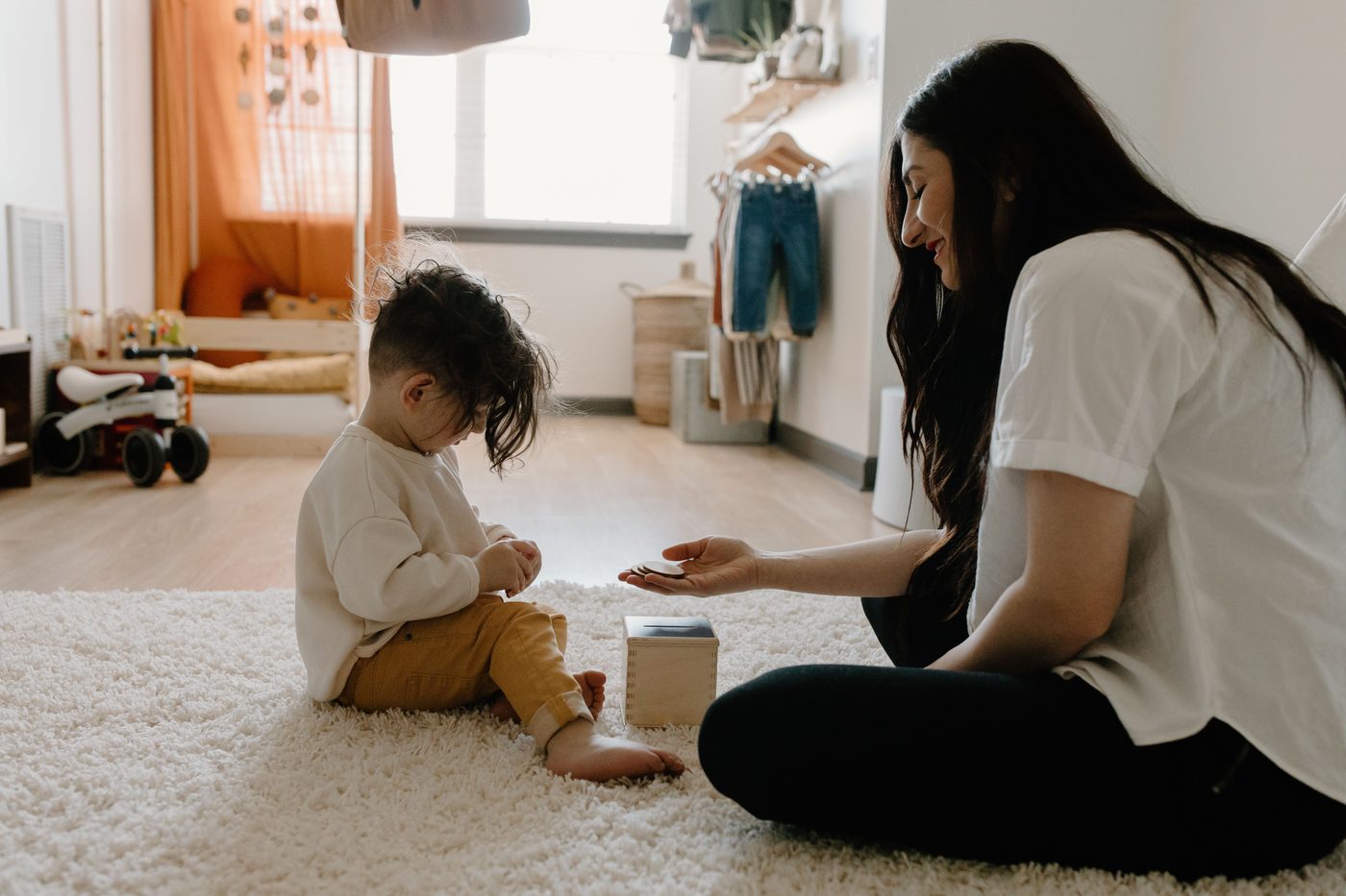 A mother and child play with an educational toy in a cozy indoor setting