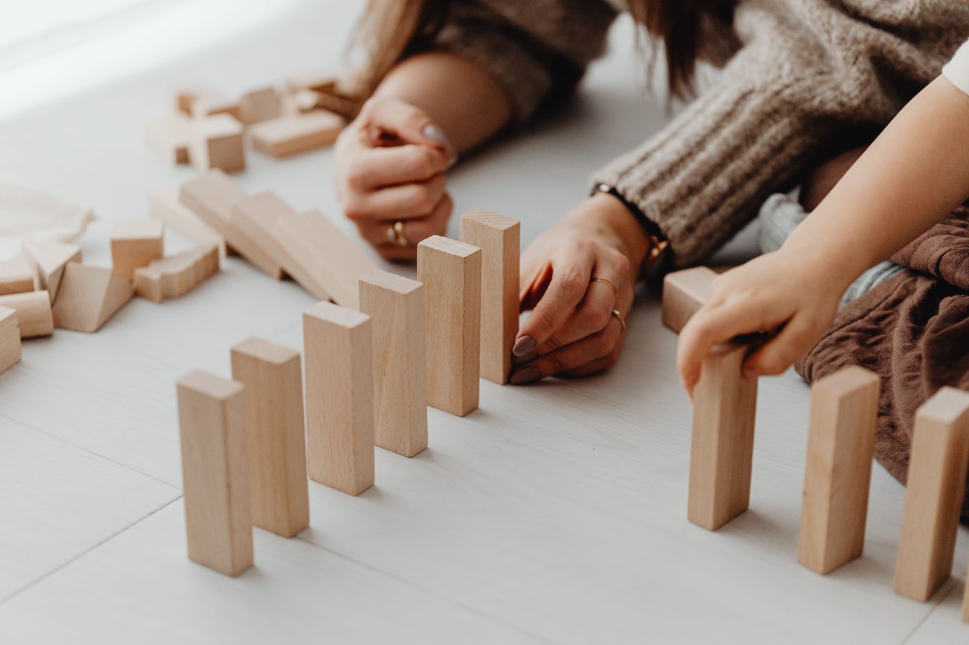 A child and parent engaging in creative play with wooden blocks indoors
